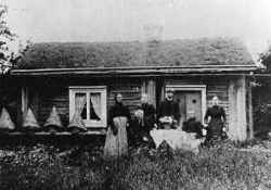 Personer framf�r Bj�rklundsstugan i Ljungstorp. �r det bikupor som syns p� b�nken till v�nster? - klicka f�r att f�rstora
