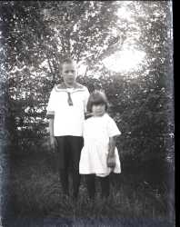 En pojke och en flicka framf�r en h�ck - klicka f�r att f�rstora
