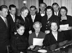 Klassfest med s�ng till piano f�r eleverna i �rskursen 1923-24 i Landslagens skola i Kvistbro. Kvinnan i mitten vid pianot �r l�raren Olga Johansson/Ahlberg och till h�ger om henne sitter Ragnhild Hagberg/Andersson. St�ende fr�n v�nster �r Einar Nilsson, ok�nd, ok�nd, Sven Larsson och Sven-Axel Larsson. Bilden �r troligen spegelv�nd. - klicka f�r att f�rstora