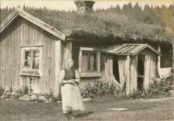 Bocka- eller Geta-Johanna i Lekhyttan framf�r sin byggnad - klicka f�r att f�rstora
