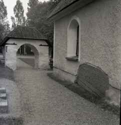 Täby kyrka med stiglucka i bakgrunden och runsten i kyrkväggen - klicka f�r att f�rstora