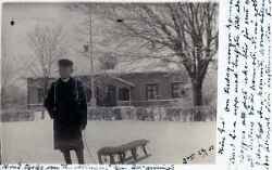 Vinterbild med pojke med k�lke framf�r byggnad - klicka f�r att f�rstora